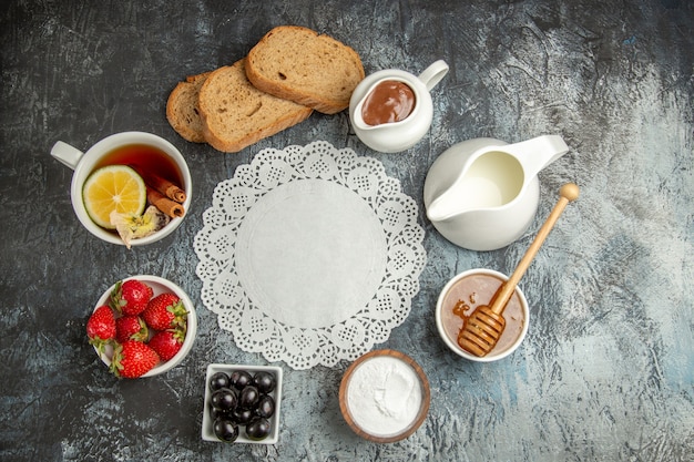 Top view cup of tea with olives and fruits on a dark surface morning breakfast food