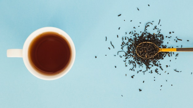 Top view cup of tea with spoon full of dry leaves