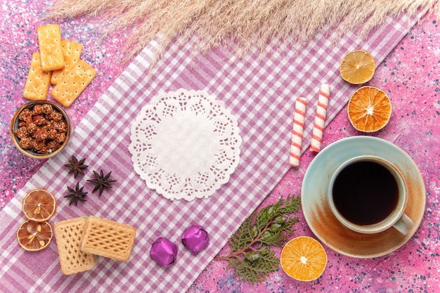 Top view cup of tea with waffles and crackers on a pink