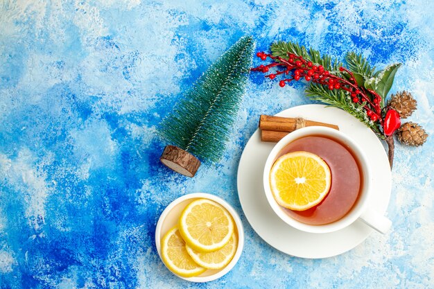 Top view cup of tea xmas tree branch cut lemons on saucer on table with copy place