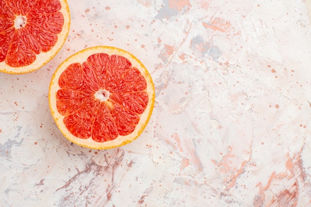 Free photo top view cut grapefruits on nude surface with copy space