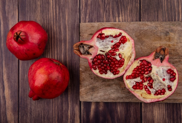 Free photo top view cut in half pomegranate on cutting board on wooden wall