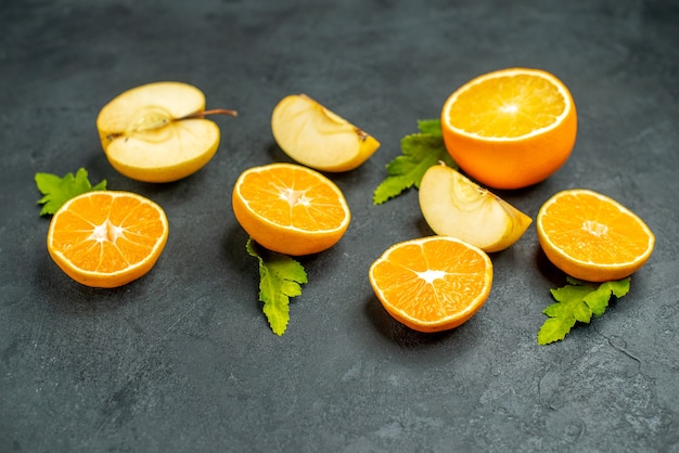 Top view cut oranges and apples on dark surface