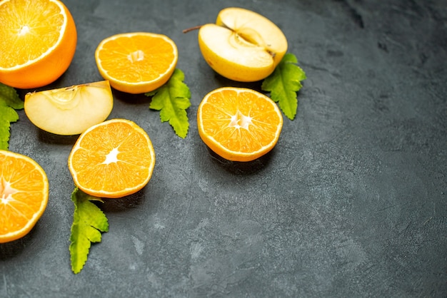 Top view cut oranges and apples on dark surface