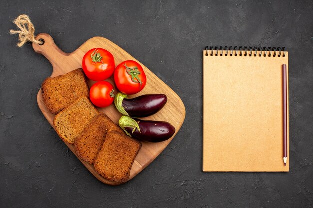 Top view dark bread loafs with tomatoes and eggplants on the dark background salad health ripe meal