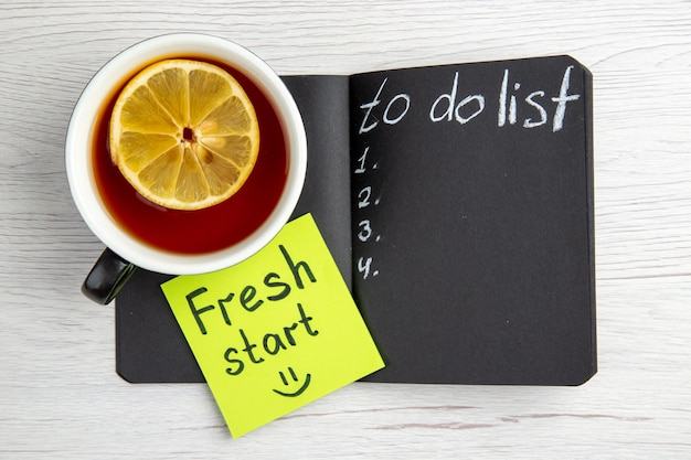 Top view dark open notepad with cup of tea and motivation notes on the white background business worker regime job office plan school day