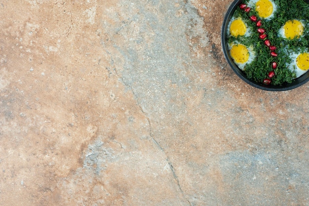 Top view of dark pan with omelet and greens .