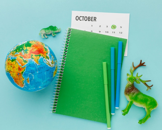 Free photo top view of deer figurine with planet earth and notebook for animal day