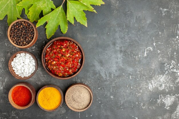 Top view delicious adjika in wooden bowl different spices in small bowls on grey background