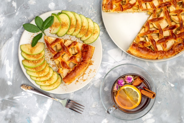 A top view delicious apple cake inside plate with tea and fresh green apple on the grey desk cake biscuit sugar 