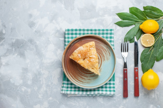 Free photo top view delicious apple pie sliced inside plate with lemons on light desk pie cake sweet bake biscuit