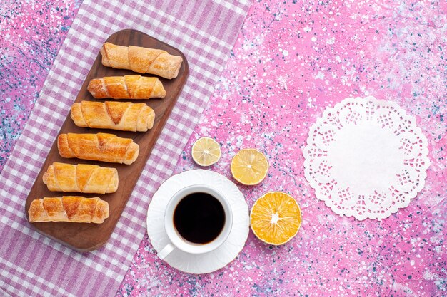 Top view delicious bagels with cup of tea on the pink background.