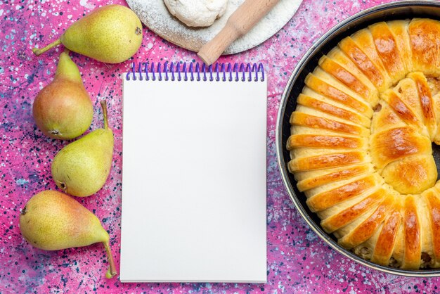 top view of delicious baked pastry bangle formed inside pan with notepad and pears on light desk, pastry cookie biscuit sweet sugar