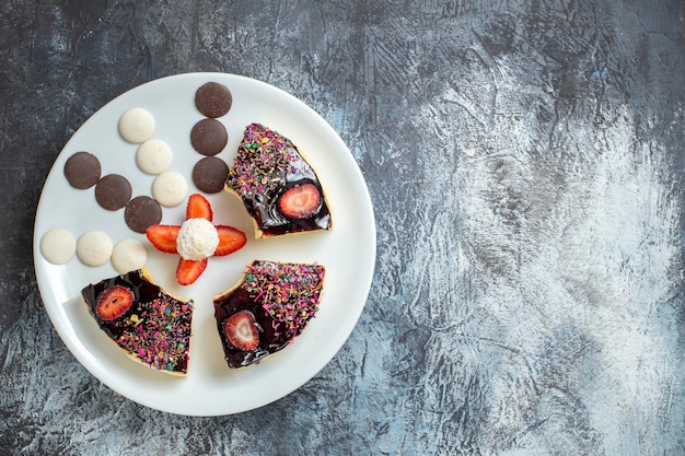 Top view delicious cake slices with little cookies on a dark surface