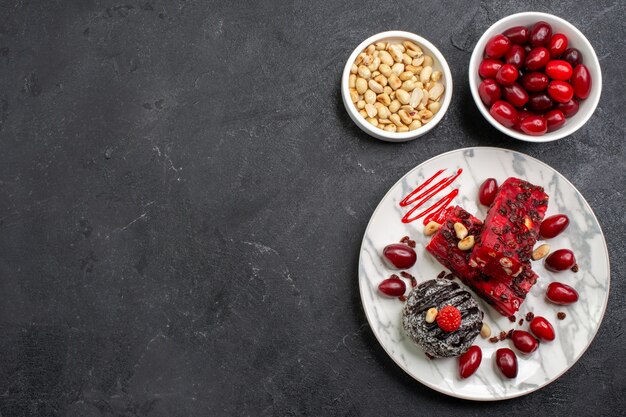 Top view delicious cake slices with nuts and dogwoods on grey space