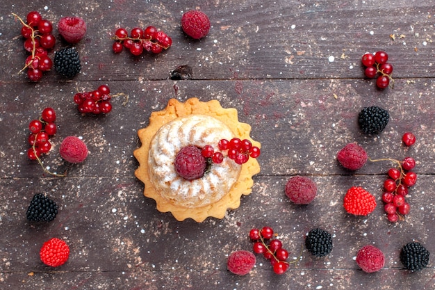 top view of delicious cake sugar powdered along with differented berries spread all over the brown desk, berry fruit cream bake biscuit