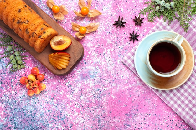 Top view delicious cake sweet and yummy with plum teas and sweet cherries on pink desk.