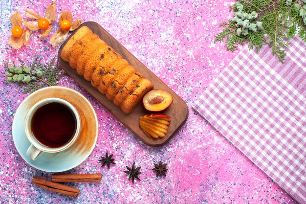 Top view delicious cake sweet and yummy with plums cinnamon and tea on pink desk.