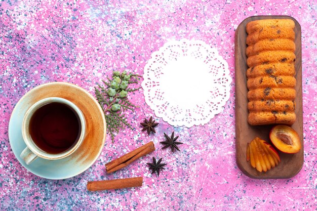 Top view delicious cake sweet and yummy with plums and cup of tea on pink desk.