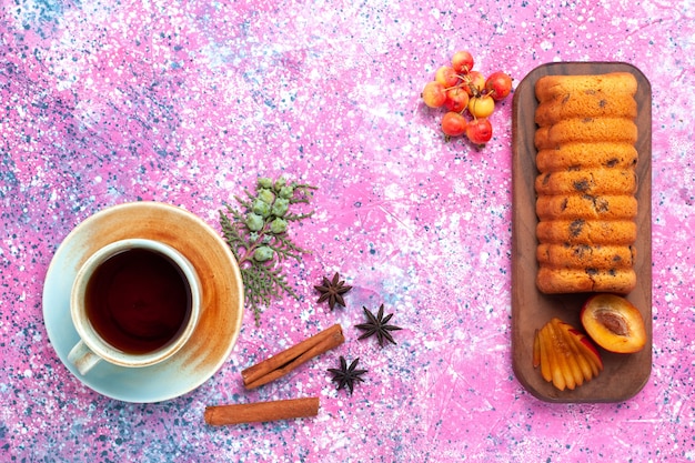 Top view delicious cake sweet and yummy with plums and cup of tea on the pink desk.