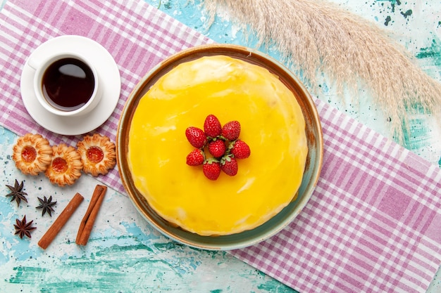 Top view delicious cake with yellow syrup fresh red strawberries and cup of tea on blue surface biscuit cake bake sweet sugar