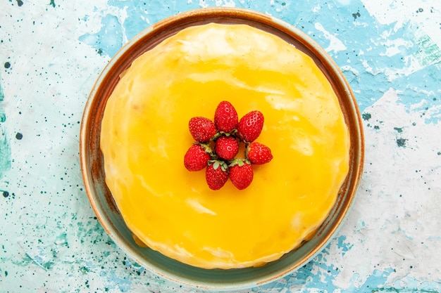 Top view delicious cake with yellow syrup and red strawberries on the blue surface biscuit cake bake sweet pie sugar tea