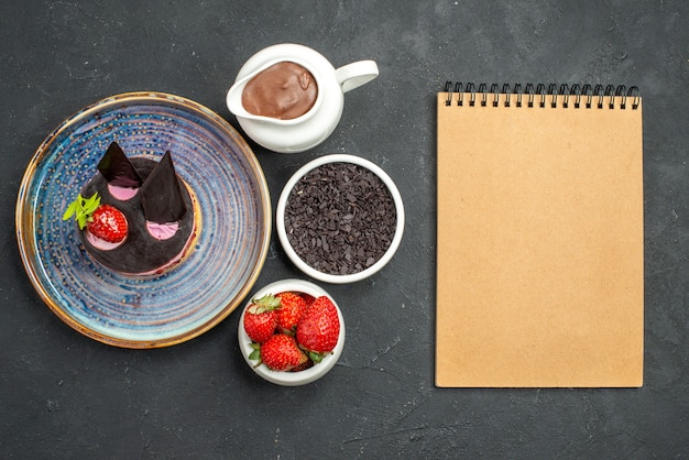 Free Photo top view delicious cheesecake with strawberry and chocolate on plate bowls with chocolate strawberries on dark isolated background