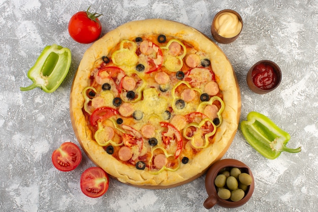 Top view delicious cheesy pizza with olives sausages and tomatoes on the grey desk fast-food italian dough meal