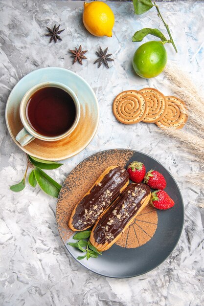 Top view delicious choco eclairs with tea on light white table cookie dessert cake