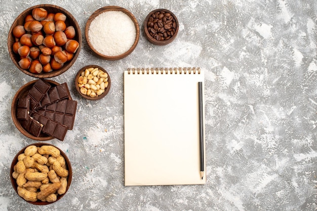 Free Photo top view of delicious chocolate bars with hazelnuts and peanuts on the white surface