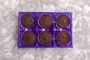 Free photo top view delicious chocolate brownies inside purple package on the light background sweet bake dough chocolate