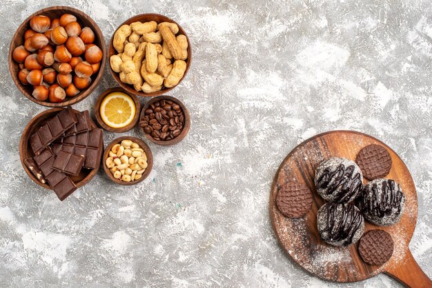 Top view of delicious chocolate cakes with cookies and peanuts on the white surface