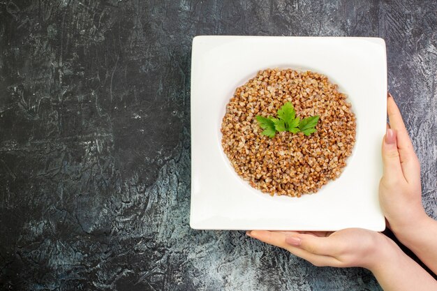 Top view delicious cooked buckwheat inside plate on light-grey background calorie food meal color photo dish bean