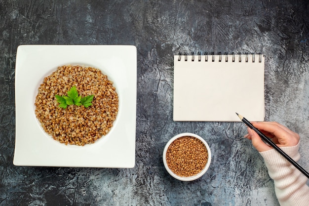 Top view delicious cooked buckwheat inside plate on the light-grey background calorie meal color photo dish bean food