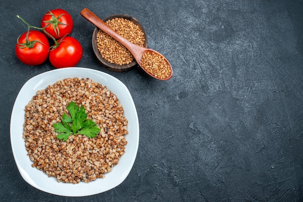 Top view delicious cooked buckwheat with fresh tomatoes on dark grey space