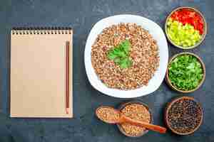 Free photo top view delicious cooked buckwheat with greens on grey desk