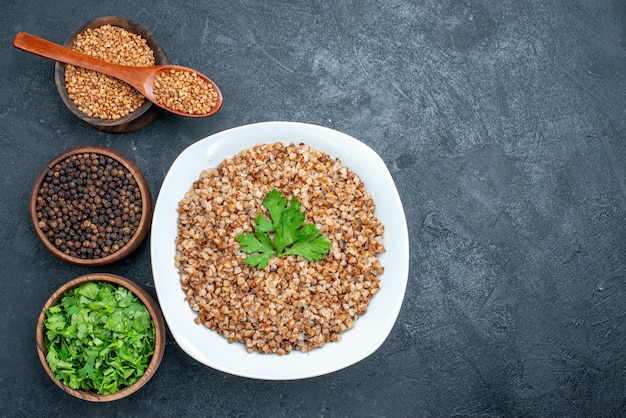 Top view delicious cooked buckwheat with greens on grey space