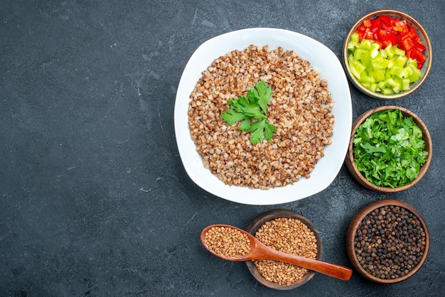 Top view delicious cooked buckwheat with greens on the grey space