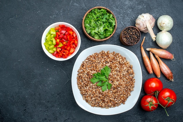 Free photo top view delicious cooked buckwheat with tomatoes and greens on grey space