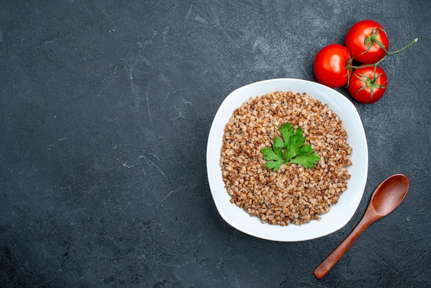 Top view delicious cooked buckwheat with tomatoes on grey desk