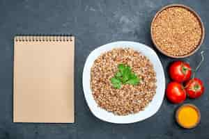 Free photo top view delicious cooked buckwheat with tomatoes on grey space