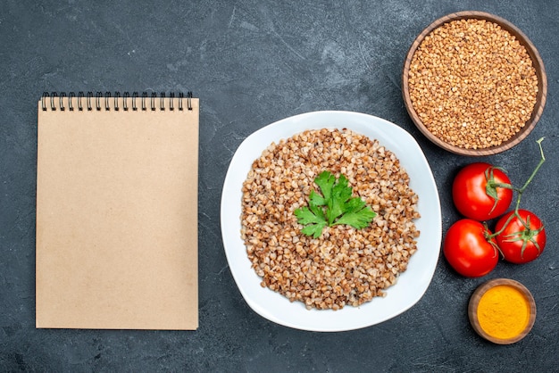 Top view delicious cooked buckwheat with tomatoes on grey space