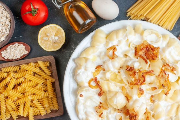 Free photo top view delicious cooked dough with raw pasta vegetables seasonings and eggs on a dark table