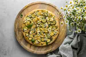 Free photo top view of delicious cooked pizza with bouquet of chamomile flowers