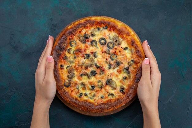 Top view of delicious cooked pizza with olives and cheese on the dark blue desk