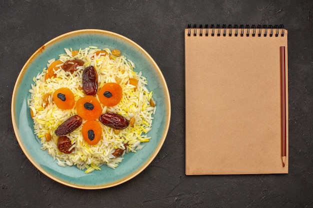 Free photo top view of delicious cooked plov rice with different raisins inside plate on a dark grey surface