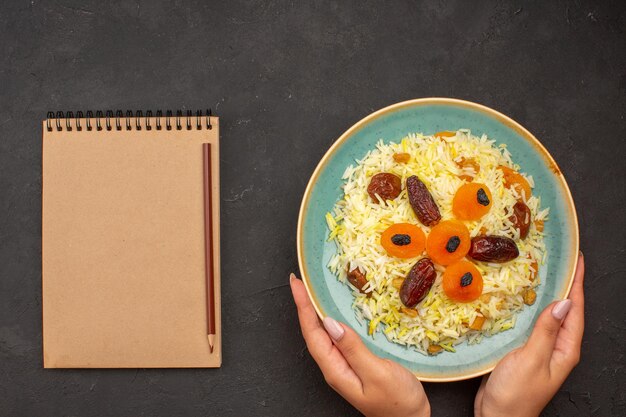 Free Photo top view of delicious cooked plov rice with different raisins inside plate on grey surface