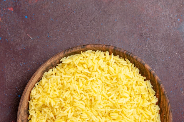 Top view delicious cooked rice inside brown plate on dark desk