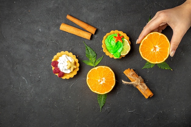 Free photo top view of delicious cookies cinnamon limes and half cut oranges with leaves on dark background