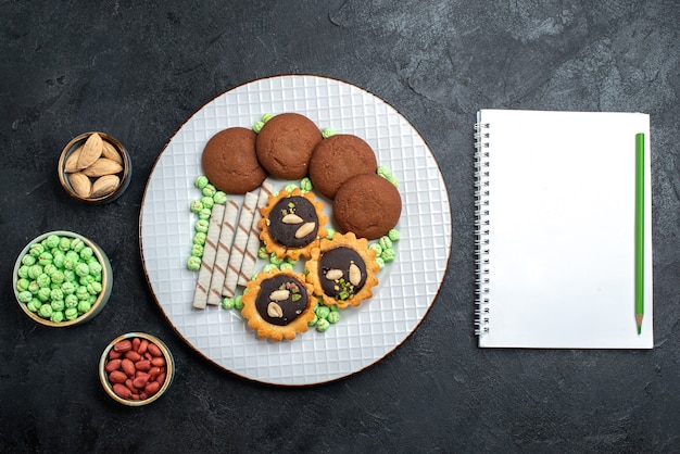 Free Photo top view delicious cookies with different candies on dark grey desk sugar biscuit sweet cake pie tea cookie